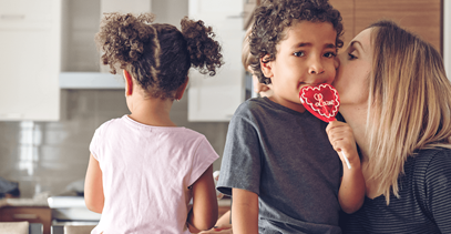mom-kissing-son-on-cheek-with-heart-lollipop